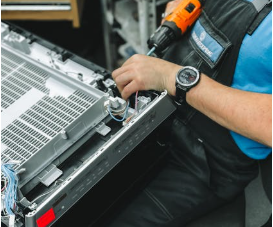 Technician carefully working on an appliance repair using tools in a workshop