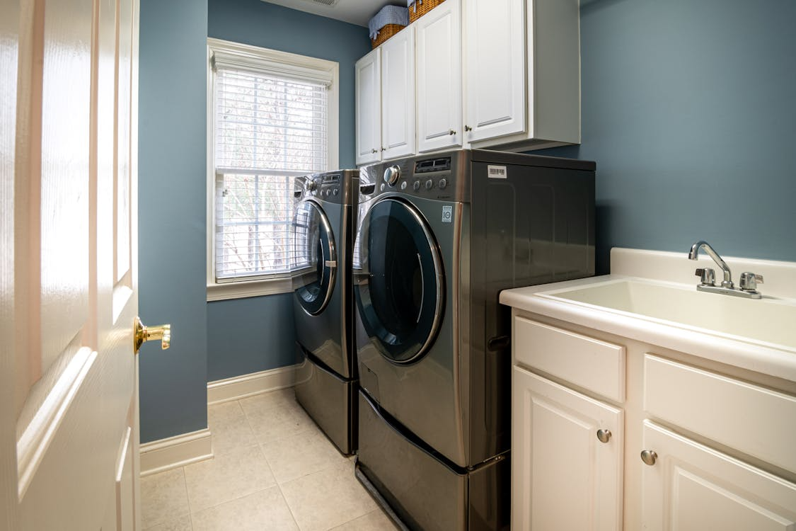 Modern laundry room with front-load washer and dryer beside utility sink