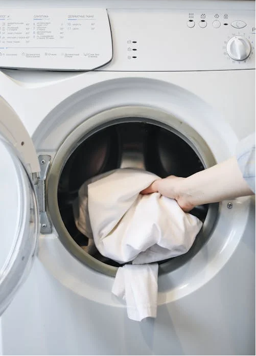 Hand placing laundry into the front-load washing machine drum